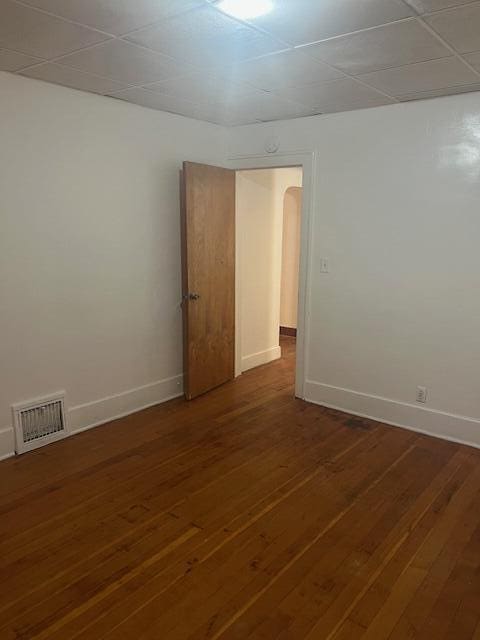 spare room featuring baseboards, wood-type flooring, and arched walkways