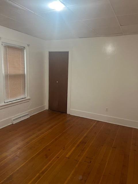 spare room featuring wood-type flooring and baseboards
