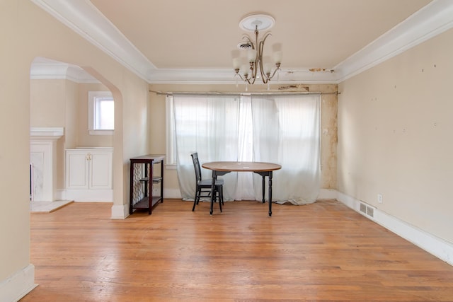 dining space with light hardwood / wood-style floors, ornamental molding, and an inviting chandelier