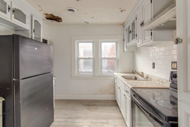 kitchen with premium range hood, white cabinetry, decorative backsplash, black appliances, and sink