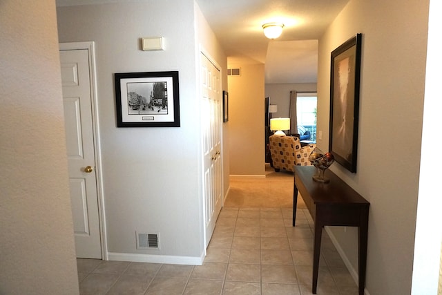 hall featuring light tile patterned flooring, baseboards, and visible vents