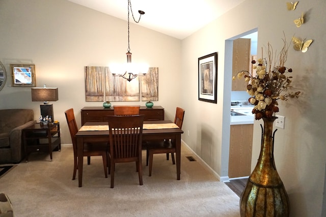 dining room with vaulted ceiling, a chandelier, and carpet