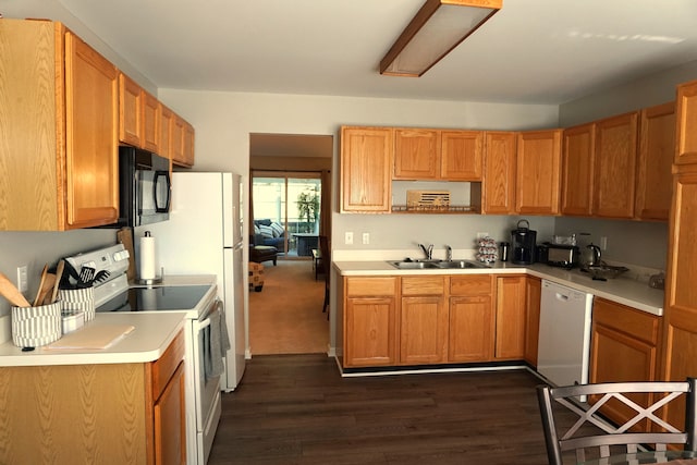 kitchen with white appliances, light countertops, dark wood-type flooring, and a sink