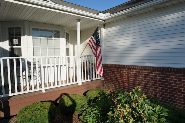 property entrance featuring covered porch and brick siding