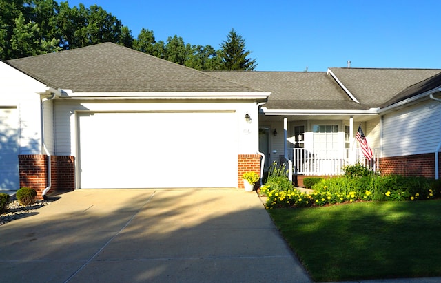 ranch-style house with an attached garage, brick siding, driveway, and roof with shingles