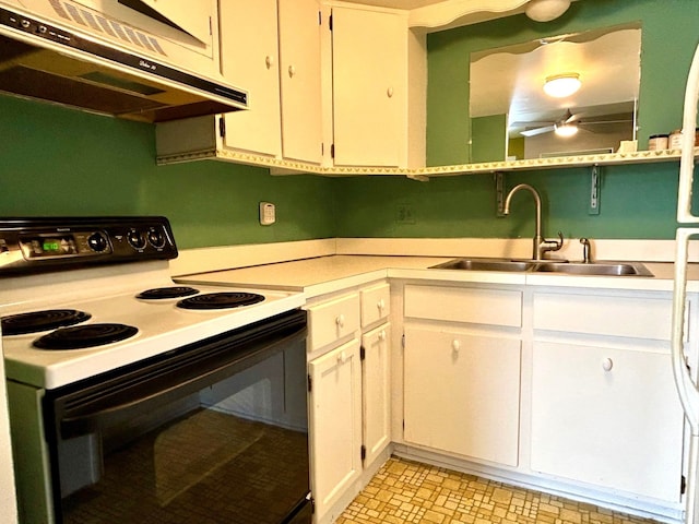 kitchen with under cabinet range hood, light countertops, range with electric stovetop, white cabinetry, and a sink