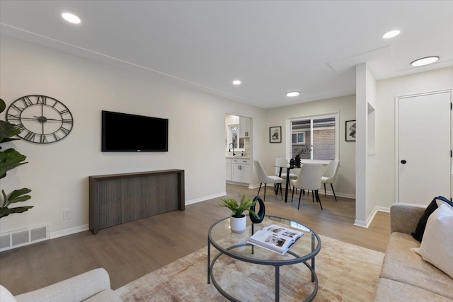 living area featuring visible vents, recessed lighting, baseboards, and wood finished floors