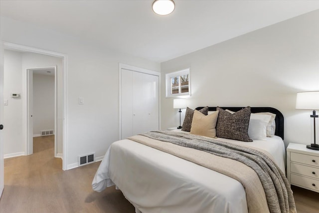 bedroom featuring visible vents, a closet, and wood finished floors