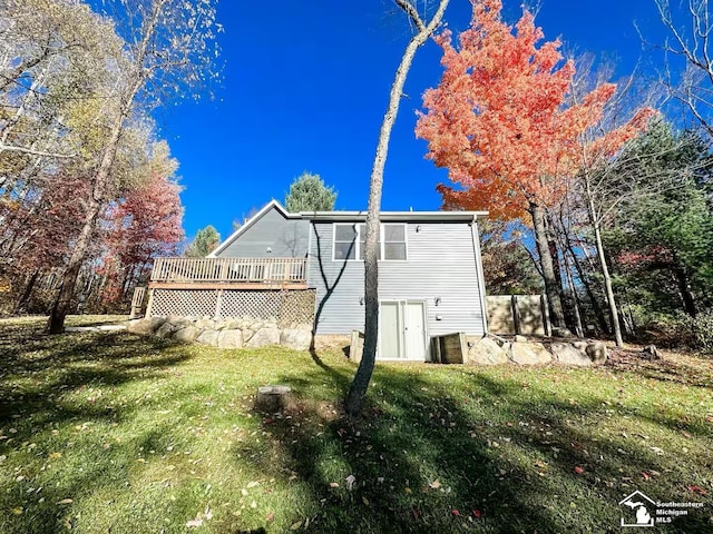 rear view of house featuring a lawn and a deck