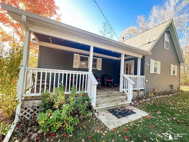 back of property with covered porch and a lawn