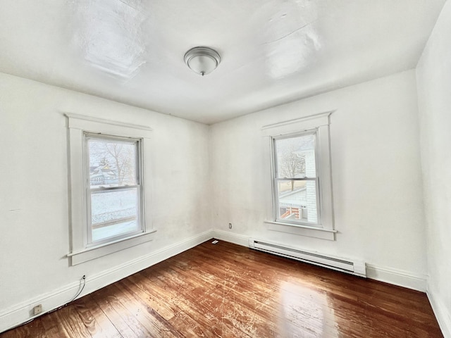 spare room featuring baseboard heating and wood-type flooring