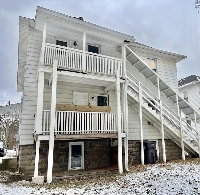 snow covered back of property with a balcony