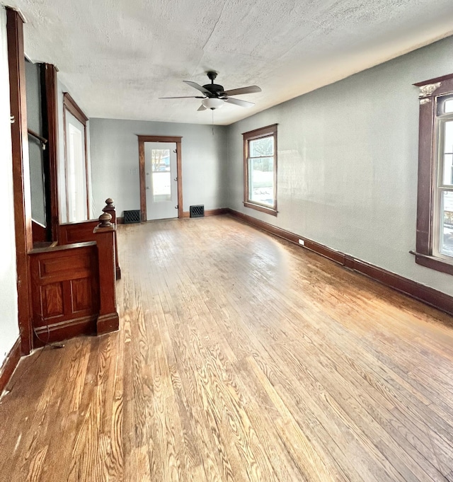 spare room with a textured ceiling, ceiling fan, a healthy amount of sunlight, and wood-type flooring