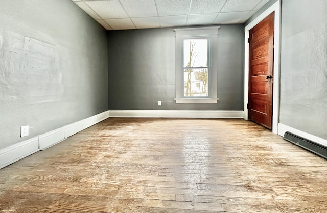 unfurnished room with light wood-type flooring and a paneled ceiling