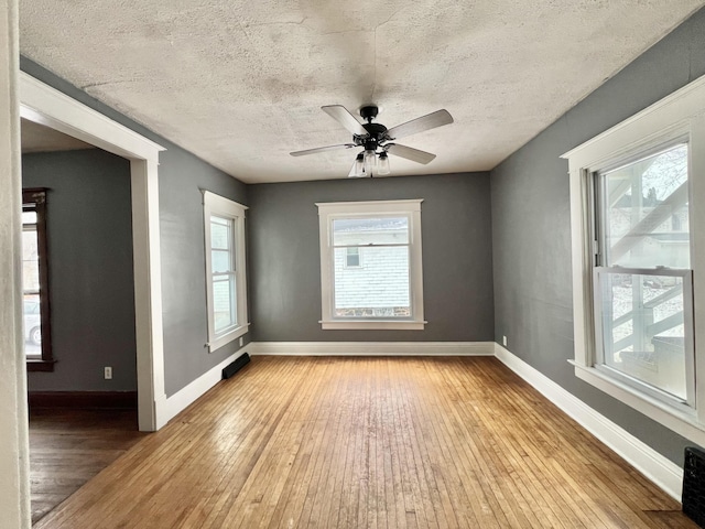 unfurnished room with ceiling fan, a healthy amount of sunlight, light wood-type flooring, and a textured ceiling