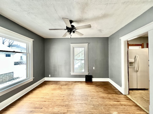 empty room featuring ceiling fan, a textured ceiling, and light hardwood / wood-style flooring