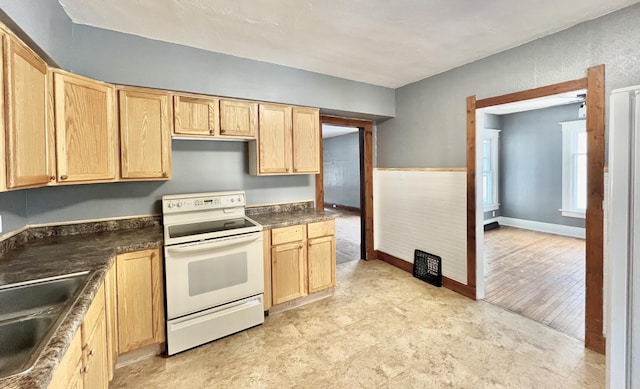 kitchen featuring light brown cabinetry, sink, and electric stove