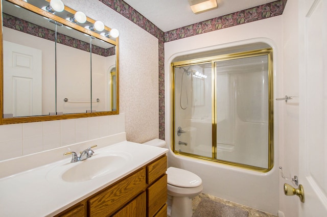 full bathroom featuring vanity, combined bath / shower with glass door, and toilet