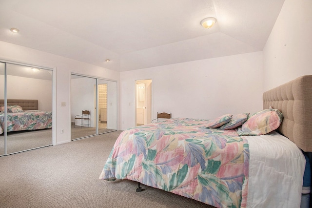 carpeted bedroom featuring lofted ceiling and two closets