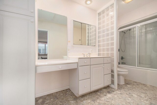 full bathroom featuring vanity, combined bath / shower with glass door, and toilet