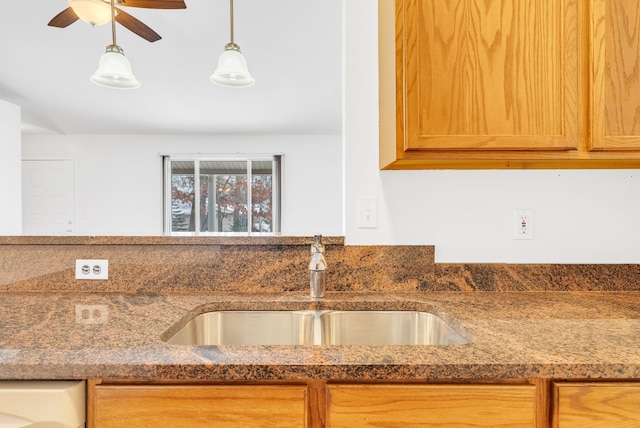 kitchen featuring ceiling fan, sink, and stone counters