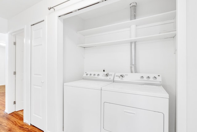 clothes washing area with independent washer and dryer and light hardwood / wood-style floors