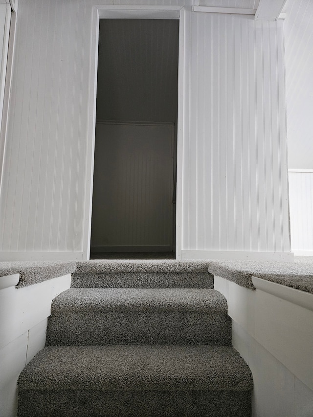 stairway featuring wood walls