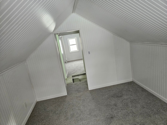 additional living space featuring lofted ceiling and dark colored carpet