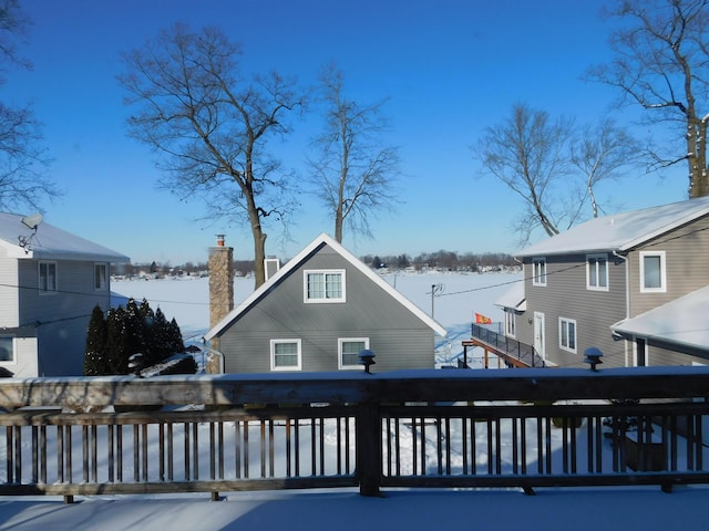 snow covered back of property with a wooden deck