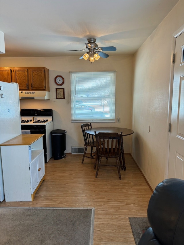 kitchen with ceiling fan, extractor fan, white fridge, light wood-type flooring, and range