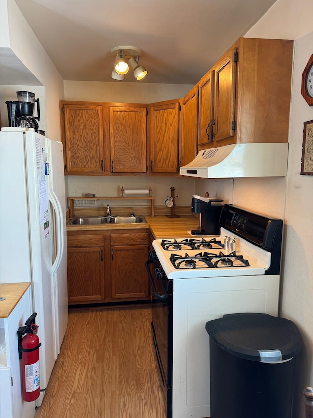 kitchen featuring white refrigerator with ice dispenser, light wood-type flooring, sink, and gas stove