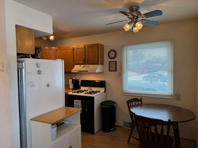 kitchen with light wood-type flooring, ceiling fan, white refrigerator, and gas stove