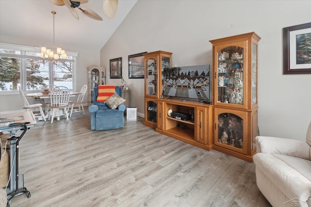 living area featuring light hardwood / wood-style floors, high vaulted ceiling, and ceiling fan with notable chandelier