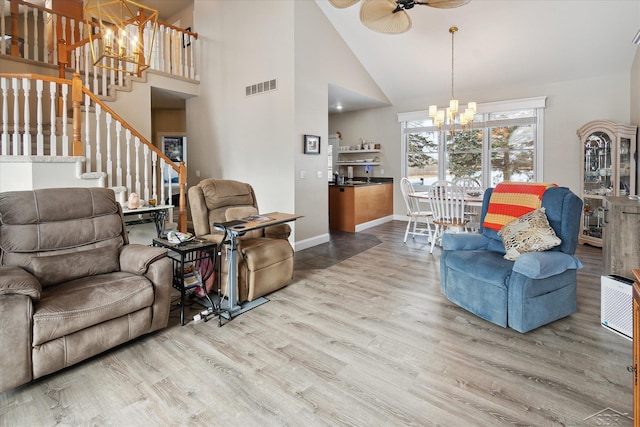 living room with ceiling fan with notable chandelier, hardwood / wood-style flooring, and high vaulted ceiling