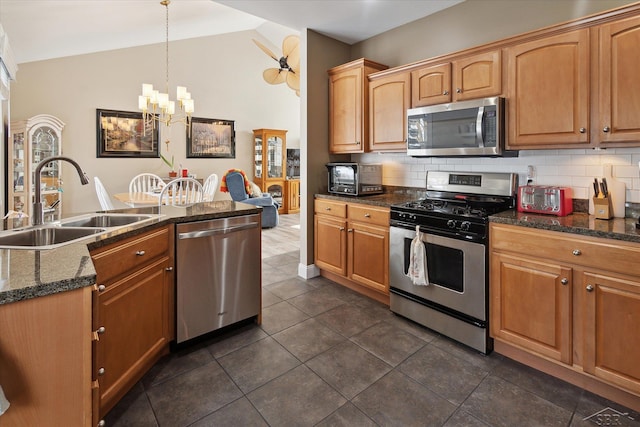 kitchen with lofted ceiling, backsplash, pendant lighting, sink, and stainless steel appliances