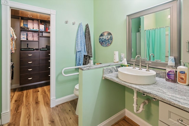 bathroom with toilet, sink, curtained shower, and hardwood / wood-style flooring