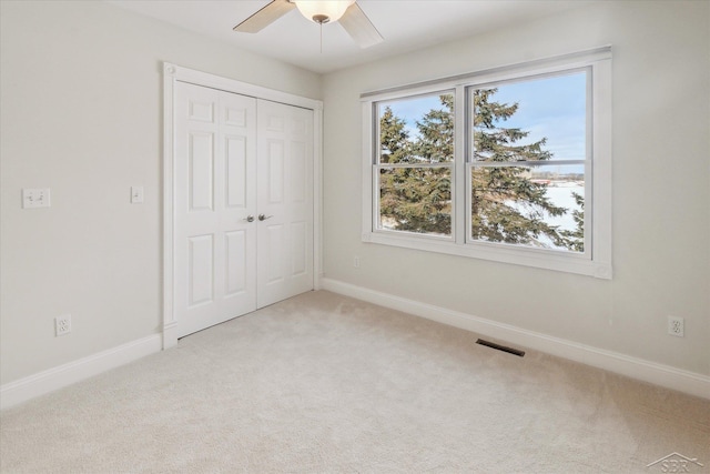 unfurnished bedroom with ceiling fan, light colored carpet, and a closet