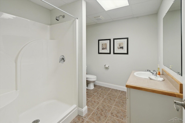 bathroom with a shower, a drop ceiling, toilet, and vanity