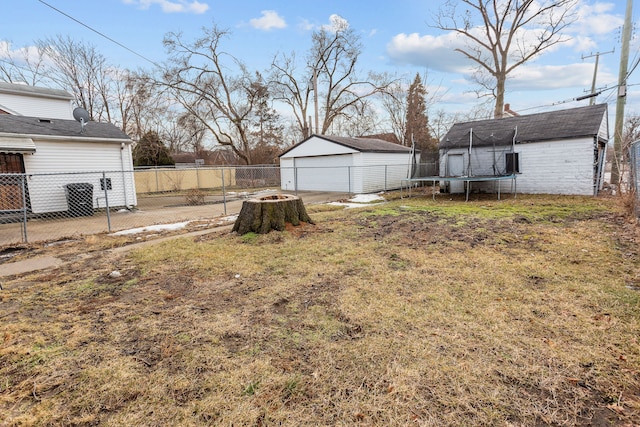 view of yard with an outbuilding, a trampoline, fence, and a garage