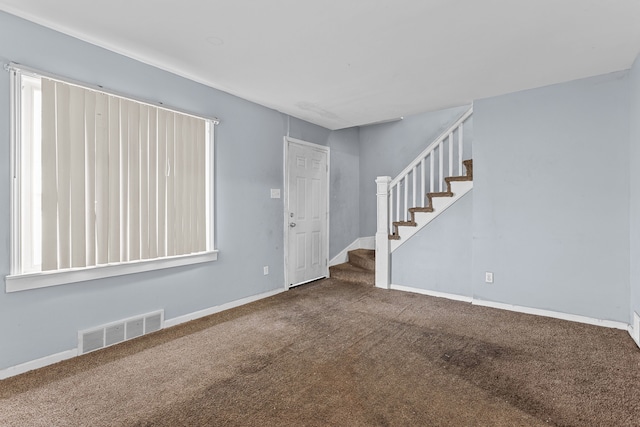 carpeted spare room with visible vents, stairway, and baseboards