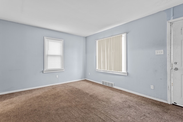 empty room featuring carpet, visible vents, and baseboards