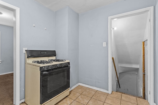 kitchen featuring light tile patterned floors, gas stove, and baseboards