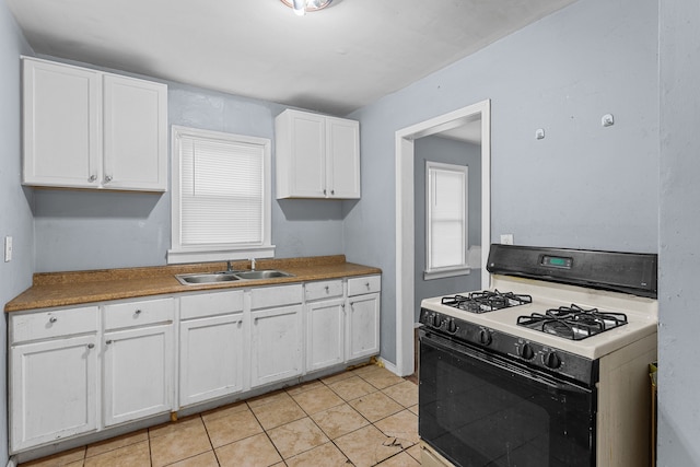 kitchen featuring gas stove, white cabinetry, a sink, and light tile patterned floors