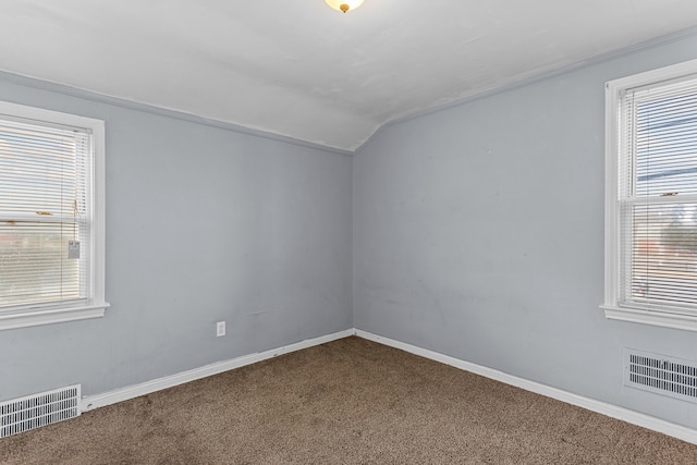 spare room with lofted ceiling, dark carpet, visible vents, and baseboards