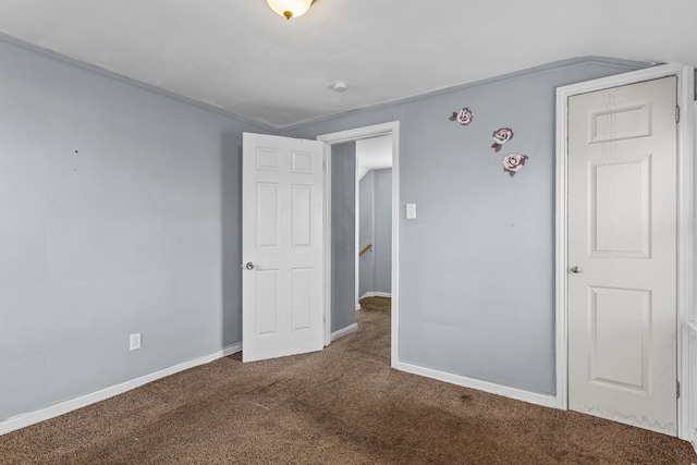 unfurnished bedroom featuring dark carpet and baseboards