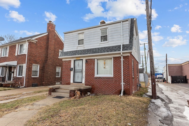 view of front of home with roof with shingles and brick siding