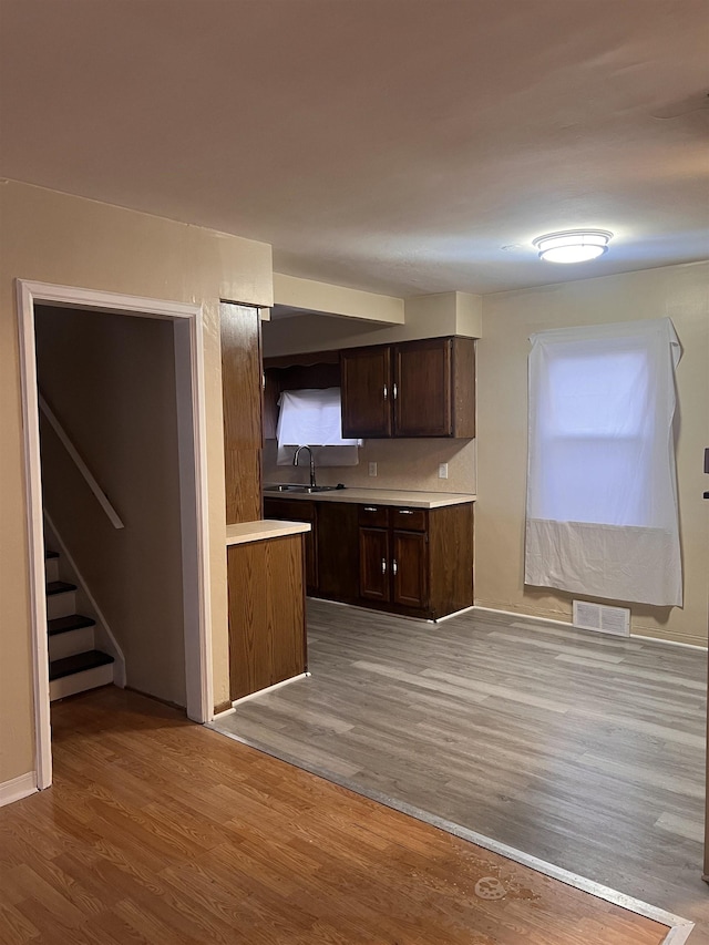 kitchen featuring dark brown cabinetry, sink, and light hardwood / wood-style flooring