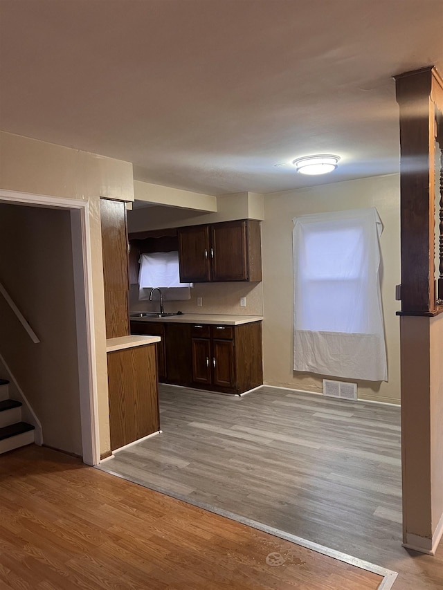 kitchen featuring sink, dark brown cabinetry, tasteful backsplash, and light wood-type flooring