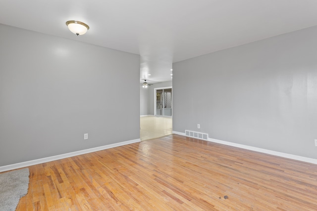 unfurnished room featuring a ceiling fan, baseboards, visible vents, and light wood-type flooring