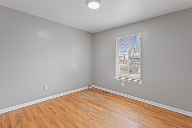 spare room with light wood finished floors, visible vents, and baseboards